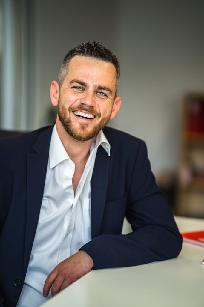 pexels-photo-12437056-12437056-1 Business professional in suit smiling confidently in a modern office environment.